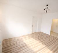 Ein Zimmer in einer 2-Zimmer-Wohnung mit einem Boden in Holzoptik und einer Leuchte.