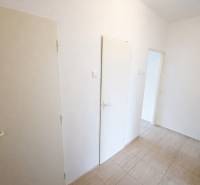 Flur in einer 2-Zimmer-Wohnung mit weißen Türen und Fliesen.