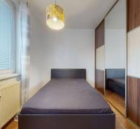 Einzelbett am Fenster, Einbauschrank und Boden mit Holzdekor in einer 3-Zimmer-Wohnung.