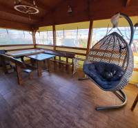 Eine Oase der Ruhe mit einem Hängesessel und Holzmöbeln auf einem Boden mit Holzdekor in den Gärten.