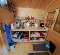 Holzküche mit Geräten, Regalen und Spüle im Garteninterieur.