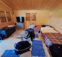 Ein Zimmer im Garten mit einem Tisch, Stühlen und zwei Betten mit bunten Decken.