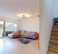 Innenraum eines Einfamilienhauses: Sofa, Bücherregal, Treppe mit Holzboden und Pflanze.