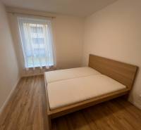 Schlafzimmer mit Bett, Holzboden in einer 2-Zimmer-Wohnung.