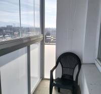 Ein verglaster Balkon mit Aussicht und einem Plastikstuhl, Teil einer 2-Zimmer-Wohnung.