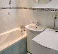 Badezimmer einer Zweizimmerwohnung mit Badewanne, Waschbecken und Waschmaschine.