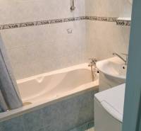 Badezimmer in einer 2-Zimmer-Wohnung mit Badewanne und hellen Fliesen.