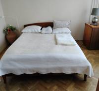 Schlafzimmer mit Doppelbett, Holzboden und Nachttisch in einer Zweizimmerwohnung.