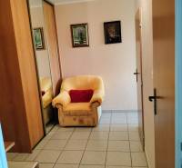 Ein Stuhl bei der Eingangstür mit Fliesenboden in einer Zwei-Zimmer-Wohnung, ein Spiegelschrank.