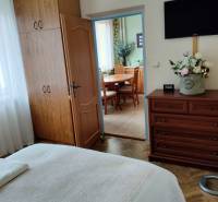 Schlafzimmer mit Einbauschrank in einer 2-Zimmer-Wohnung, Boden mit Holzdekor, Türen führen in die Küche.
