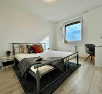 Schlafzimmer in einer 2-Zimmer-Wohnung mit Holzboden und Metallbett.