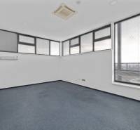 Büros mit Teppichboden und großen Fenstern mit Jalousien.