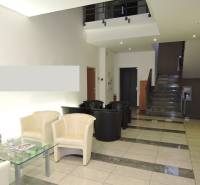 Empfangsbereich mit bequemen Sesseln, Glastisch und Treppen in Büros.