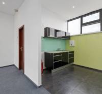 Eine kleine Küche mit einer glänzenden schwarzen Küchenzeile in Büros mit Teppichboden.