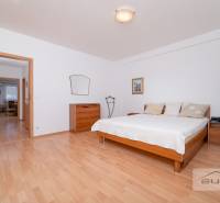 Schlafzimmer in einer 3-Zimmer-Wohnung mit Bett, Kommode und Boden in Holzoptik.