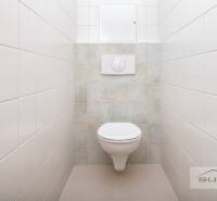 Toilette mit Fliesen und hängendem WC in einer 3-Zimmer-Wohnung.