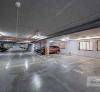 Unterirdischer Parkplatz mit markierten Parkplätzen und geparkten Autos und Motorrädern.