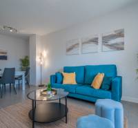 Wohnzimmer in einer 2-Zimmer-Wohnung mit einem blauen Sofa und einem Esstisch.