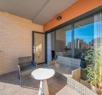 Terrasse einer 2-Zimmer-Wohnung in Alicante mit Rattansitzgruppe und Blick auf die Stadt.