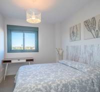 Schlafzimmer in einer 2-Zimmer-Wohnung mit gemustertem Überwurf und Dekorationen an den Wänden.