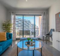 Wohnzimmer in einer 2-Zimmer-Wohnung mit Terrasse, blauem Sofa und Pflanze.