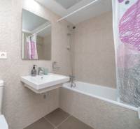 Badezimmer in einer 2-Zimmer-Wohnung mit modernen Fliesen, Badewanne und Waschbecken.