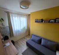 Ein Zimmer in einem Einfamilienhaus mit einem Holzboden, einem Schreibtisch und einem Sofa.