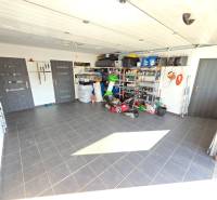 Garage in einem Einfamilienhaus mit Werkzeugen und Lagerregalen, Boden aus Keramikfliesen.