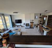 Wohnzimmer in einem Einfamilienhaus mit Sofa, Fernseher und Esstisch auf einem Boden mit Holzdekor.