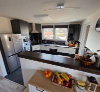 Eine Küche in einem Einfamilienhaus mit modernen Geräten, einer Theke und Obst auf dem Tisch.