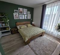 Ein Schlafzimmer in einem Einfamilienhaus mit Holzboden, grüner Wand und Blumen.