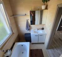 Ein Badezimmer in einem Einfamilienhaus mit einer Badewanne, einem Waschbeckenunterschrank und einem Fenster mit Licht.