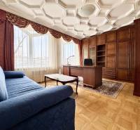 Ein Zimmer in einer 4-Zimmer-Wohnung mit einem bequemen Sofa, einem Schreibtisch und einem Boden in Holzoptik.