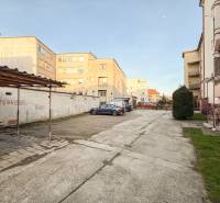 Parkplatz bei den 2-Zimmer-Wohnungen in der Hodžova-Straße in Trenčín mit Autos und Grünflächen.