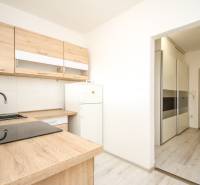 Küche einer 2-Zimmer-Wohnung mit Holzboden und hellen Möbeln.