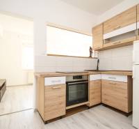 Küche in einer 2-Zimmer-Wohnung mit Holzboden und hellen Möbeln.