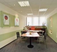 Büros mit Schreibtisch, Stühlen, an den Wänden angebrachten Dekorationen und einem Fenster mit vertikalen Jalousien.