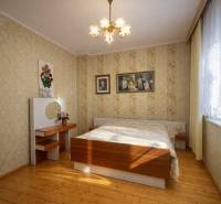 Schlafzimmer in einem Einfamilienhaus mit Holzboden und Blumenmustertapeten.