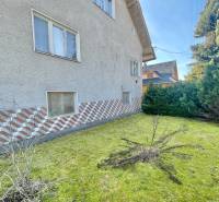 Ein Einfamilienhaus in Terchová mit einem Rasenstück, umgeben von Sträuchern und dekorativem Verkleidung.