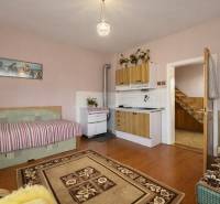 Ein Zimmer mit Küchenzeile, Sofa, Herd und Holzboden in einem Einfamilienhaus.