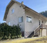 Ein Einfamilienhaus in Terchová mit großen Fenstern, einer Treppe und einem gepflegten Vorgarten.