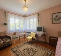 Wohnzimmer in einem Einfamilienhaus mit Teppich, Fernseher und Boden in Holzoptik.