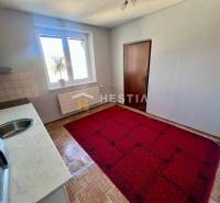 Die Küche einer 3-Zimmer-Wohnung mit Teppichboden, Holzbodenoptik und einfacher Einrichtung.