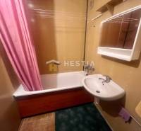 Badezimmer mit Waschbecken und Badewanne in einer 3-Zimmer-Wohnung, der rosa Vorhang fügt ein auffälliges Element hinzu.