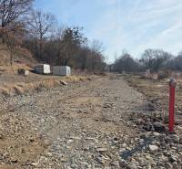 Grundstücke - Wohnen in Haniska, steiniger Weg zwischen Bäumen und Container.
