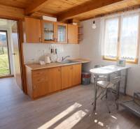 Küche in einer Hütte mit Holzdekor und Möbeln, sonnige Umgebung.