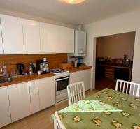 Eine Küche in einem Einfamilienhaus mit weißen Schränken, Holzelementen und einem Esstisch.