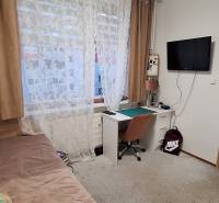 Ein Zimmer in einer 4-Zimmer-Wohnung mit einem Tisch, einem Bett und einem Fernseher, Holzboden.