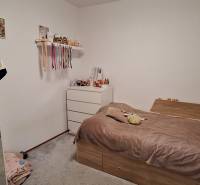 Schlafzimmer in einer 4-Zimmer-Wohnung mit begehbarem Kleiderschrank, Bett und weißer Kommode.