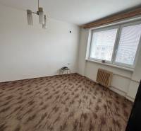 Ein Zimmer in einer Einzimmerwohnung mit einem Fenster, weißen Wänden und einem Boden in Holzoptik.